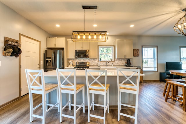 kitchen featuring plenty of natural light, backsplash, stainless steel appliances, and wood finished floors