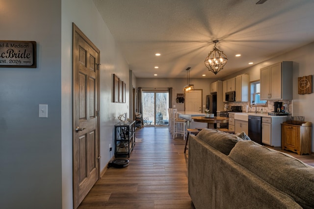 living room featuring dark wood finished floors, a notable chandelier, plenty of natural light, and recessed lighting