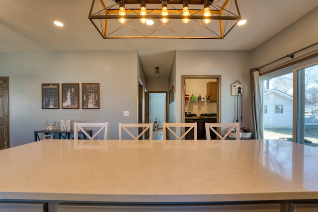 kitchen featuring recessed lighting, light stone counters, and hanging light fixtures