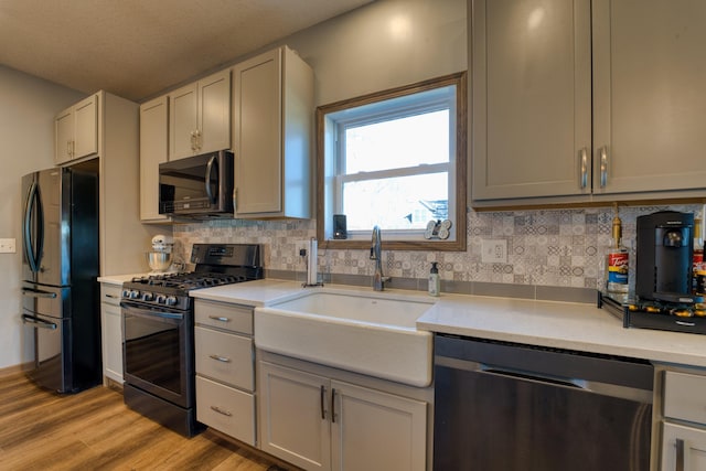 kitchen with a sink, stainless steel appliances, backsplash, and light countertops