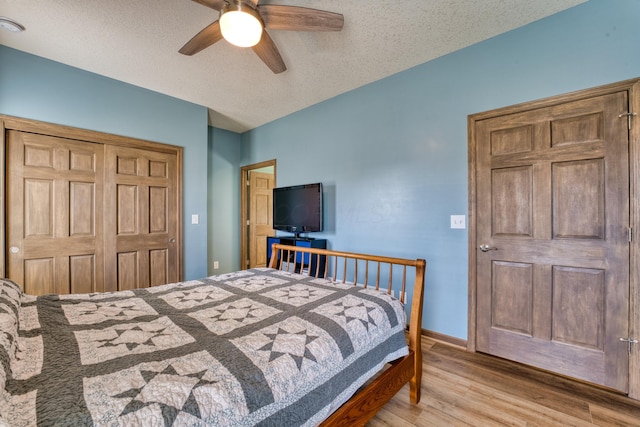 bedroom featuring a ceiling fan, wood finished floors, baseboards, a closet, and a textured ceiling