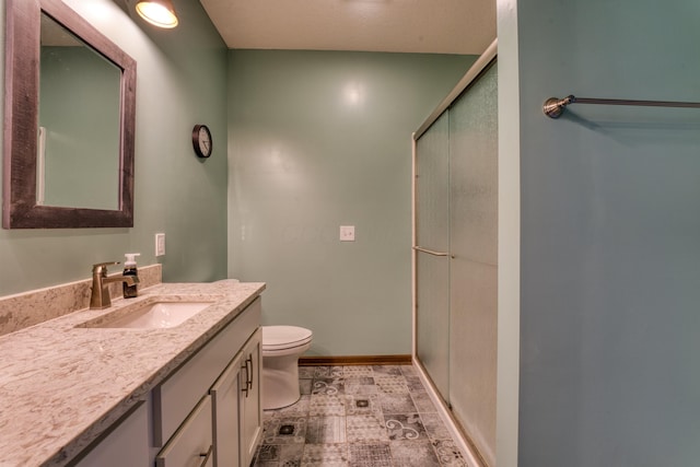 full bath featuring vanity, a shower stall, toilet, and baseboards