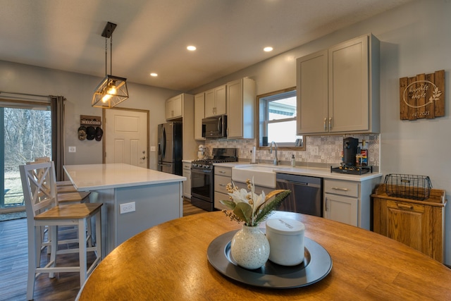 kitchen with backsplash, a kitchen island, dishwasher, gas range oven, and black fridge with ice dispenser