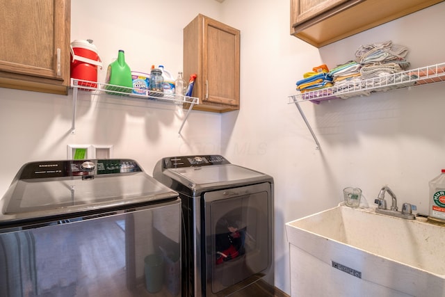 laundry room with washing machine and clothes dryer, cabinet space, and a sink