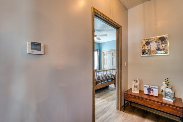 hallway with light wood-style flooring and a textured ceiling