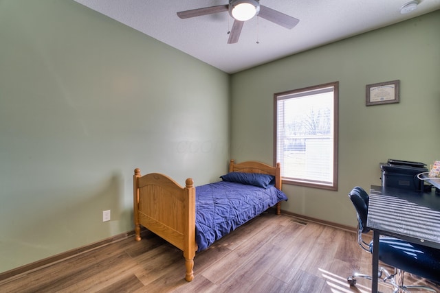 bedroom featuring visible vents, a ceiling fan, baseboards, and wood finished floors