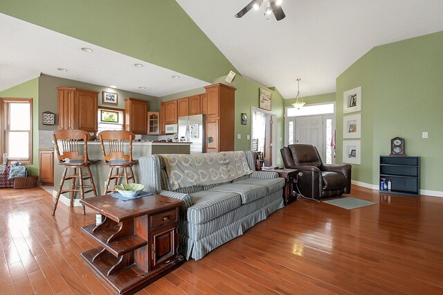 living area with light wood finished floors, baseboards, and high vaulted ceiling