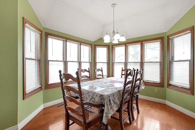 dining room featuring light wood-style floors, lofted ceiling, a notable chandelier, and baseboards