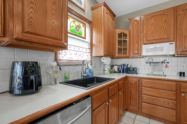 kitchen with white microwave, light countertops, a sink, and brown cabinetry