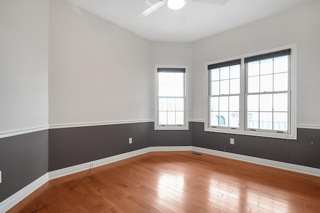 spare room with hardwood / wood-style floors, visible vents, and baseboards