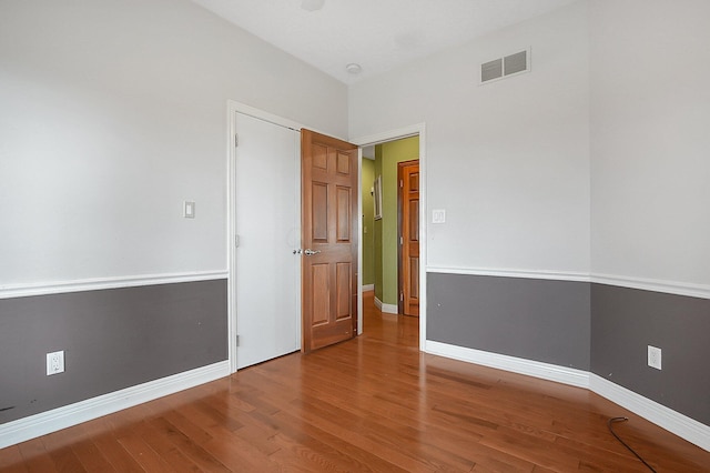 unfurnished room with visible vents, baseboards, and wood finished floors