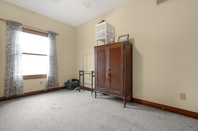 interior space featuring ceiling fan, baseboards, and light colored carpet