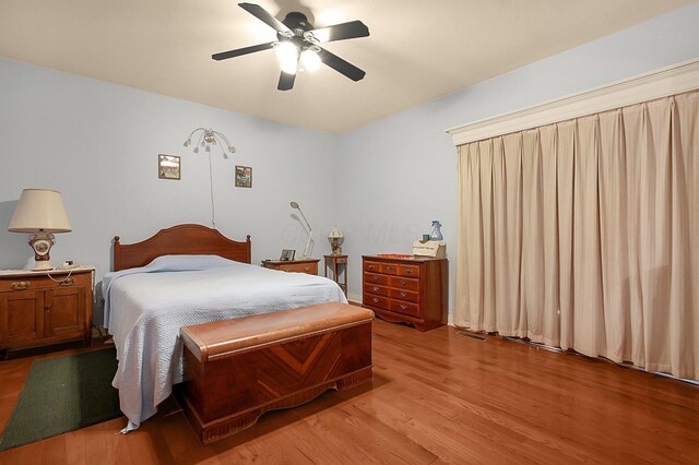 bedroom featuring light wood-style floors, visible vents, and a ceiling fan