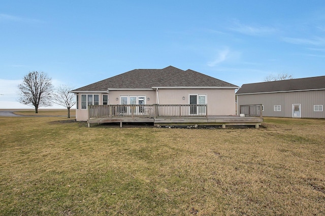 back of house with roof with shingles, a yard, a deck, and stucco siding