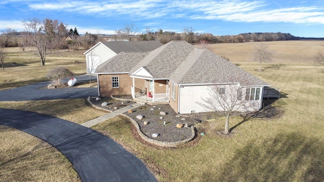 view of front of home with driveway, a shingled roof, and a front yard