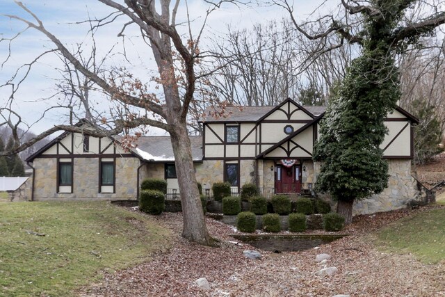 tudor-style house featuring a front yard and stone siding