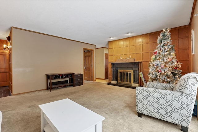 living area featuring light carpet, baseboards, ornamental molding, and a glass covered fireplace