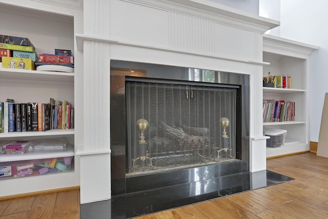 room details with a fireplace with flush hearth and wood finished floors