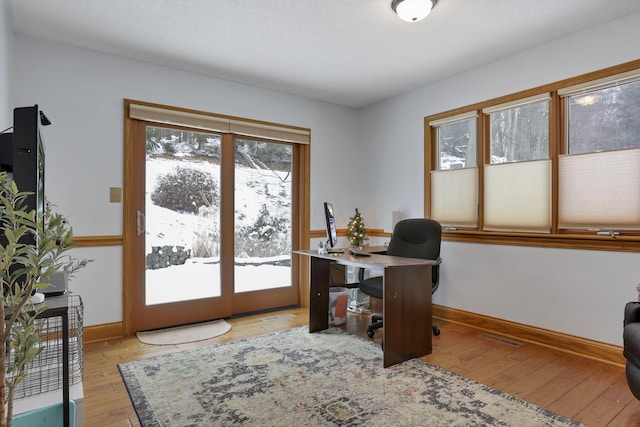 home office with light wood-type flooring, visible vents, and baseboards