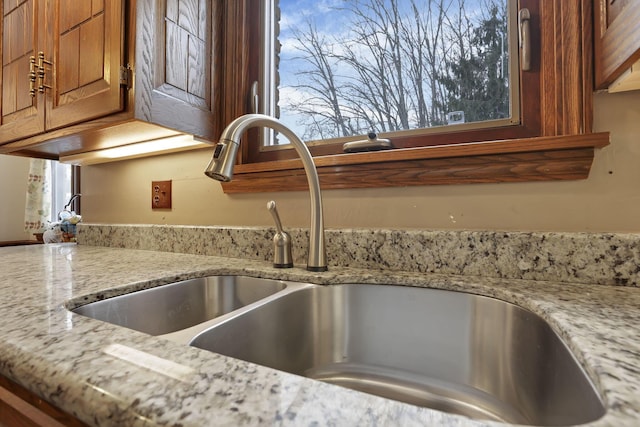 interior details with light stone countertops, brown cabinetry, and a sink