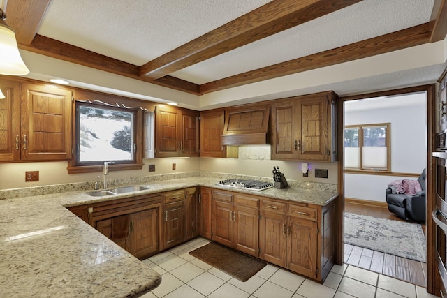 kitchen with custom range hood, beamed ceiling, a textured ceiling, stainless steel gas stovetop, and a sink