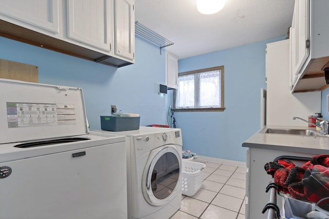 clothes washing area with light tile patterned floors, a sink, baseboards, cabinet space, and washing machine and clothes dryer