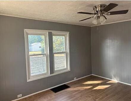 spare room with baseboards, visible vents, ceiling fan, wood finished floors, and a textured ceiling