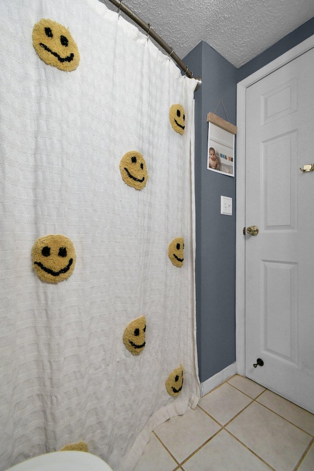 bathroom with a textured ceiling and tile patterned flooring