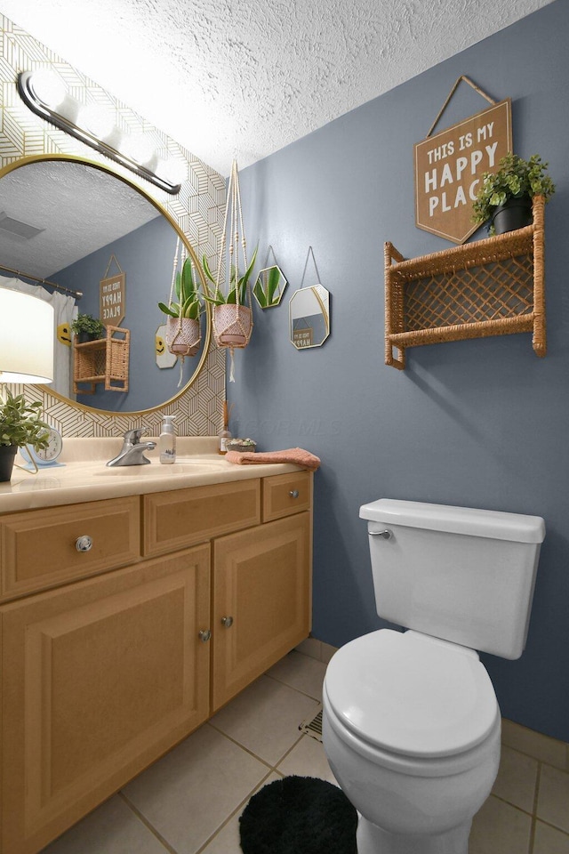 bathroom featuring toilet, tile patterned floors, a textured ceiling, and vanity