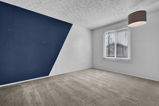 empty room featuring carpet floors, a textured ceiling, and baseboards