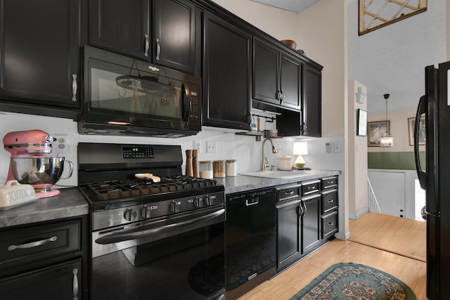 kitchen featuring black appliances, dark cabinetry, light wood-type flooring, and a sink