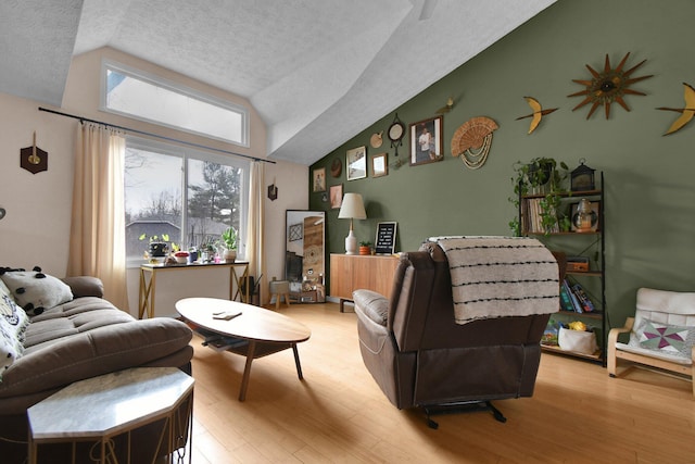 living area featuring lofted ceiling, light wood-style flooring, and a textured ceiling