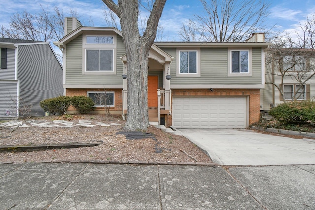 bi-level home featuring a garage, concrete driveway, brick siding, and a chimney