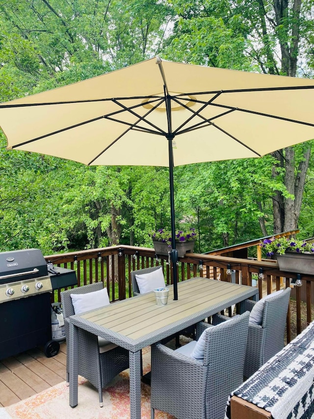 wooden deck featuring outdoor dining area, area for grilling, and a wooded view