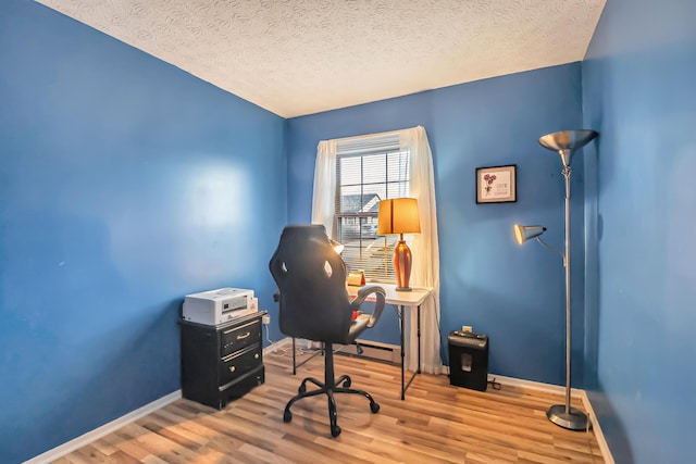 office area featuring a textured ceiling, baseboards, and wood finished floors