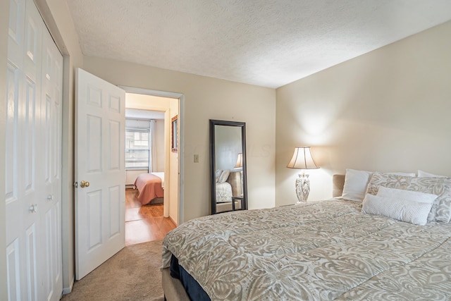 bedroom with a closet, a textured ceiling, and carpet