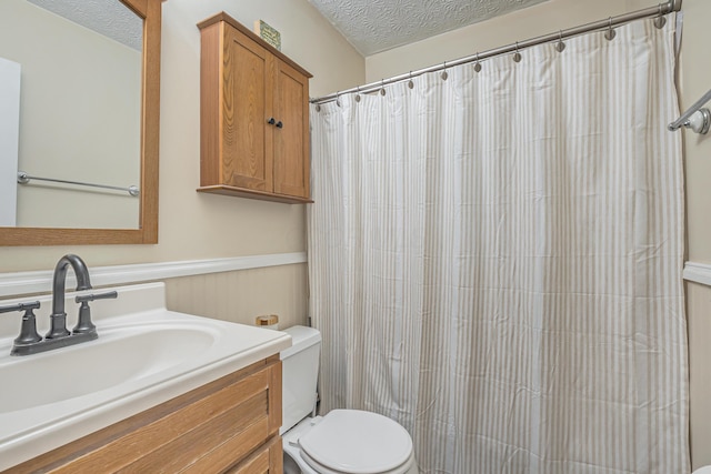 bathroom with vanity, curtained shower, toilet, and a textured ceiling