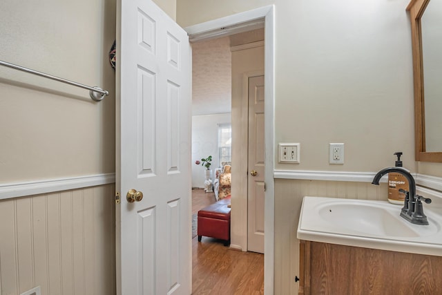 bathroom featuring vanity, wood finished floors, and wainscoting