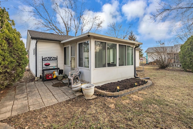 exterior space with a patio area, a lawn, and a sunroom