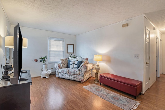 living area featuring ornamental molding, a textured ceiling, and wood finished floors