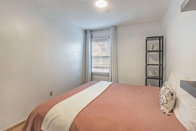 bedroom with baseboards, a textured ceiling, and wood finished floors