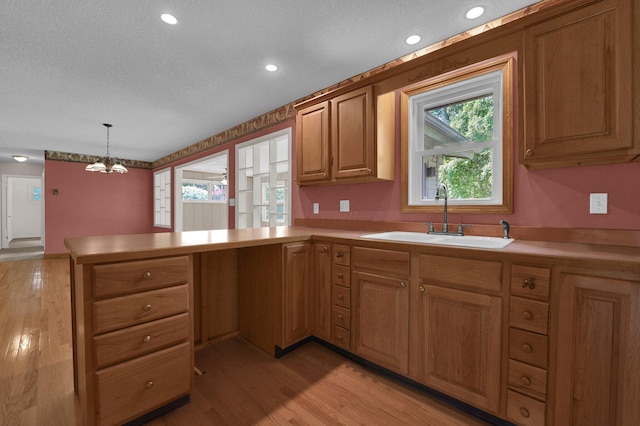 957 Sharon View Dr, Newark, OH 43055 - kitchen featuring a sink, a peninsula, a chandelier, light wood-style floors, and light countertops