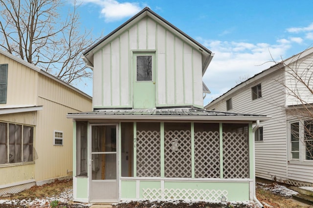 back of property with a sunroom, metal roof, and board and batten siding