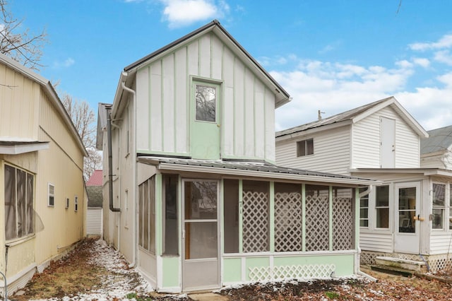 back of property featuring a sunroom, metal roof, and board and batten siding