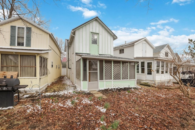 rear view of house with board and batten siding and a sunroom