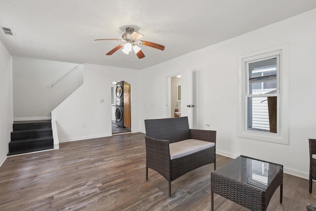 sitting room featuring arched walkways, wood finished floors, visible vents, stacked washer / drying machine, and stairway