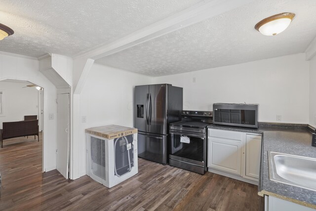 kitchen featuring dark wood-style floors, arched walkways, appliances with stainless steel finishes, a sink, and a textured ceiling