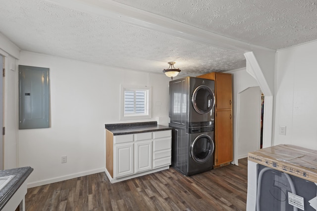 laundry area featuring laundry area, electric panel, dark wood-type flooring, stacked washer / drying machine, and a textured ceiling