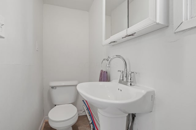 half bath with toilet, baseboards, and a sink