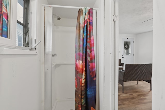 full bathroom featuring a stall shower, a textured ceiling, and wood finished floors